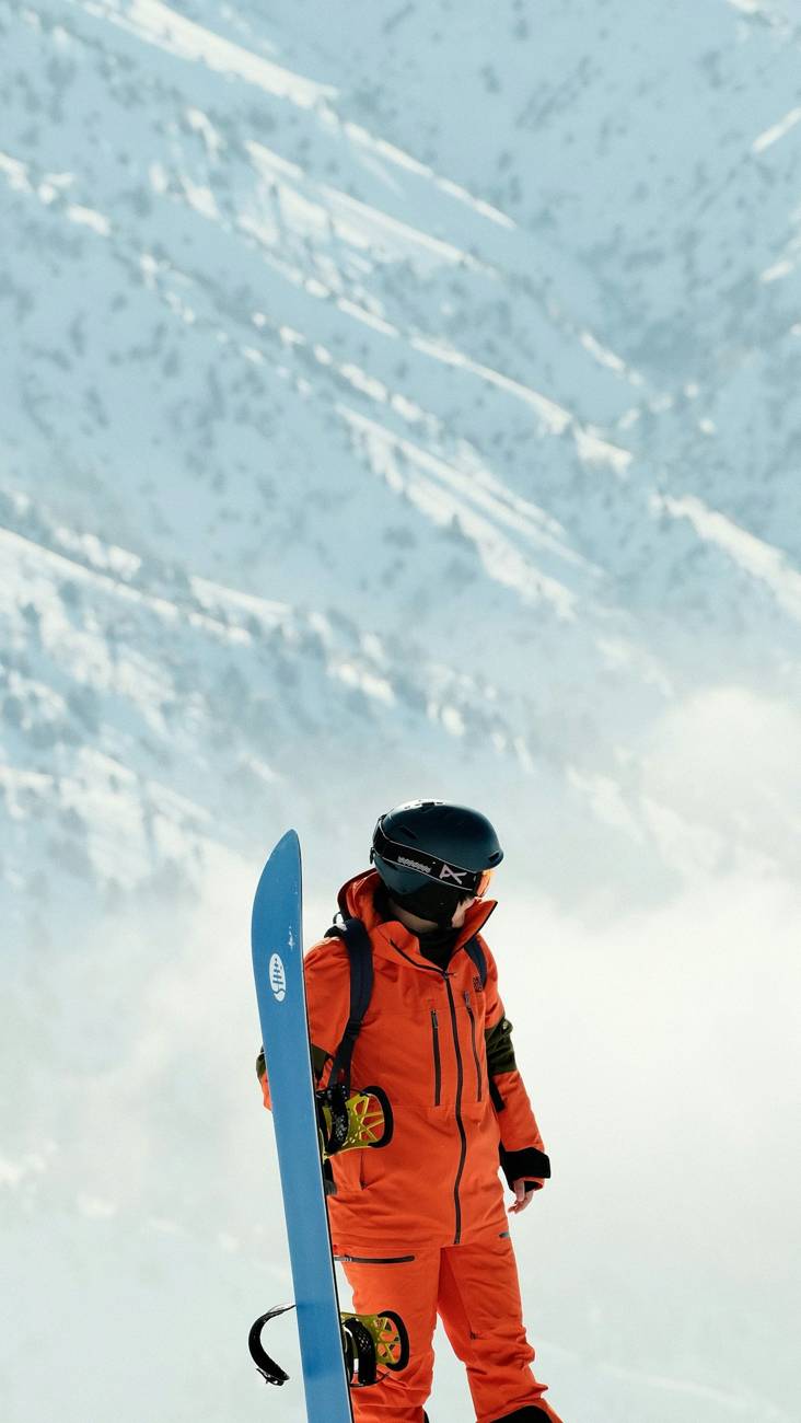 Snowboarder in orange suit holding a board