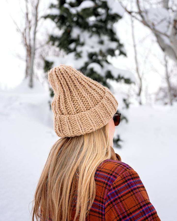 Woman in a cream knit beanie in falling snow