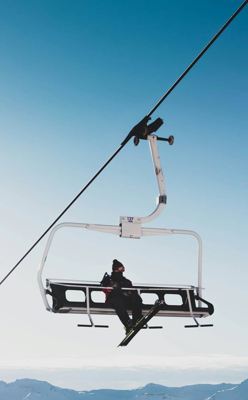 Skier on a chairlift against a white sky
